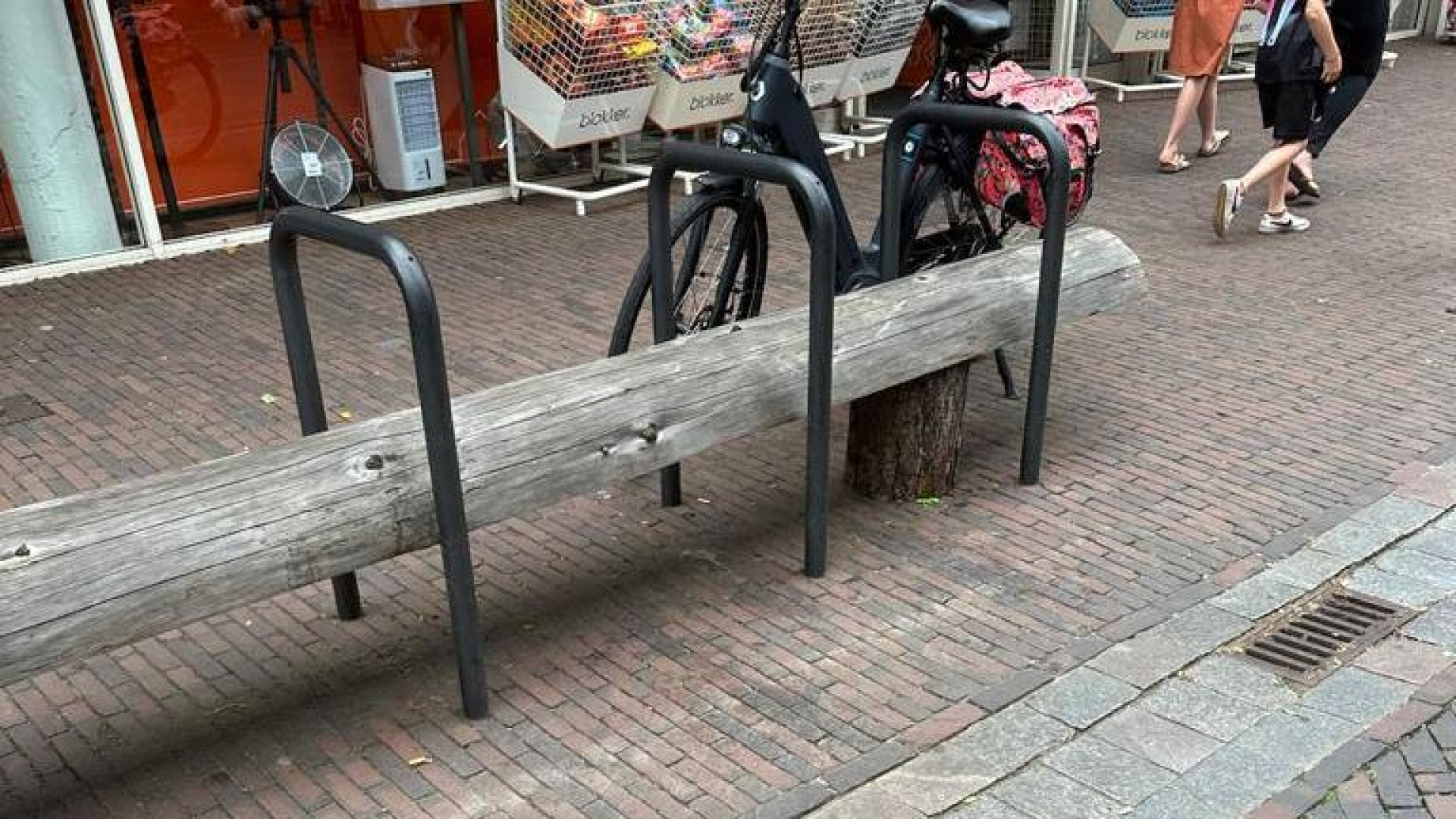 Foto: Houten boomstammen blijven zitten tussen fietsnietjes